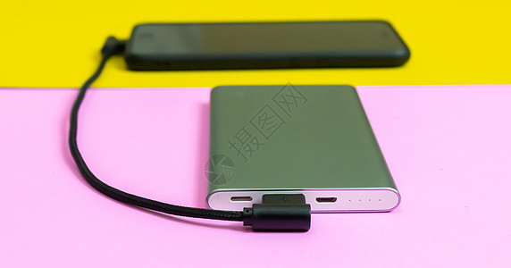 智能手机手机通过移动电源粉红色和黄色背景为电池充电电缆屏幕收费粉色白色细胞充值展示活力充电器图片