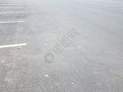 白色线条和叶叶的黑色沥青停车场图片