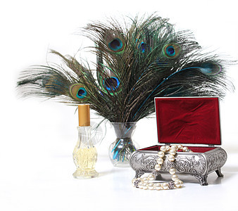 旧珠宝盒和孔雀羽毛眼睛香水风格项链热带古董蓝色盒子花瓶白色背景图片