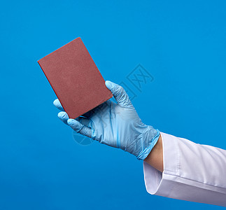 穿蓝色乳胶手套的医生持有红色封面护照图片