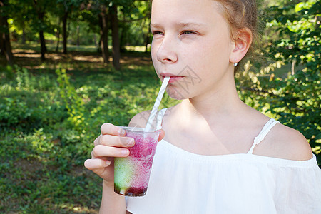 在公园里 一个女孩手里拿着一根稻草 喝着新鲜的果实饮料活动营养水果果汁橙子生活方式休闲热带玻璃情调图片