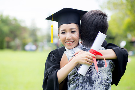 年轻女毕业生在毕业典礼上拥抱她朋友的抱抱女孩女士学校文凭微笑乐趣成功母亲庆典女性图片