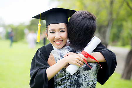 年轻女毕业生在毕业典礼上拥抱她朋友的抱抱庆典乐趣女孩成功大学校园教育女士学生帽子图片
