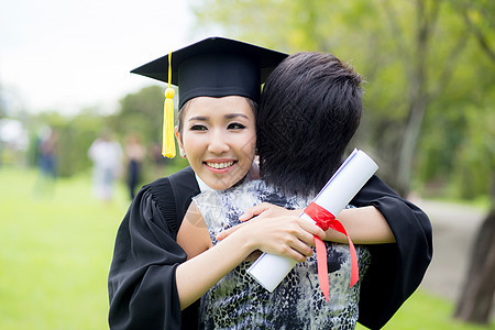 年轻女毕业生在毕业典礼上拥抱她朋友的抱抱女士女孩女性文凭大学教育乐趣帽子微笑成功图片