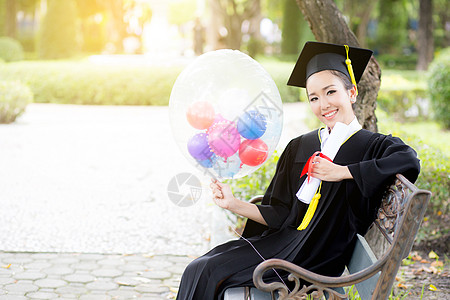 穿着学术服和学校服装的年轻快乐女毕业生肖像帽子微笑大学仪式学士文凭成人学生研究生学习图片