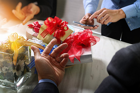使用智能手机及同事choosi赠送创意手的礼物庆典花瓶白领展示桌子快乐朋友们男人假期男性图片