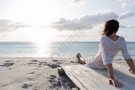 坐在海边坐着 身穿白色带子裙子 白内裤和长头发的年轻女孩在清晨风中看着地平线海岸线悲伤寂寞天空生活精神戏剧性孤独情感晴天图片