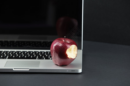 闪亮的红苹果放在开放式铝制笔记本电脑上 有选择地聚焦在黑色背景上桌子绿色家庭作业商业网络红色工作职场技术教育图片