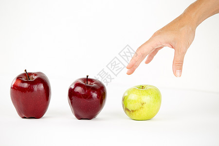 多样性的概念 一个女人的手即将抓住其他红苹果中唯一的青苹果团体营养团队歧视展示教育果味领导者水果生产图片