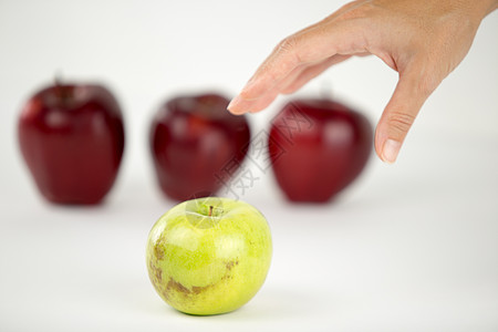 多样性的概念 一个女人的手即将抓住其他红苹果中唯一的青苹果团体展示歧视团队领导者果味水果个性生产教育图片