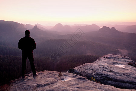 在悬崖上高高的黑人 看着日出登山 假扮自信心石头岩石男性运动日落旅行环境情感朋友冒险图片