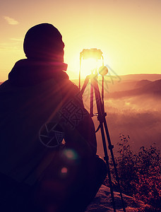 摄影师在岩石高峰用照相机拍摄照片图片