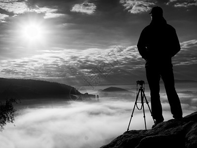 悬崖上的摄影师 自然摄影师在岩石峰顶用镜子相机拍照图片