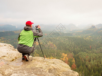 自然摄影师坐在岩石边缘拍摄照片 坐落在岩石边缘职业帝国摄影旅行记者运动员记忆艺术家记录自由职业者图片