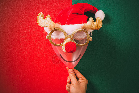 手握着圣诞眼镜 装饰驯鹿 还有卡片红色眼镜面具假期绿色空气气球潮人季节图片