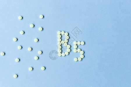 在蓝色背景上形成 B5 的黄色药片 复合维生素 营养 药品 健康的生活方式 食品添加剂 复制空间 软焦点 模糊的背景 横幅科学海图片