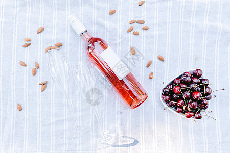 含眼镜和樱桃野餐背景的玫瑰酒瓶图片