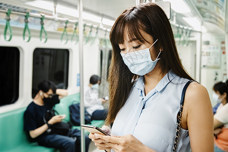 在地铁列车中戴外科面具和使用手机的亚洲年轻女乘客 女性旅客商务运输女士安全通勤者电话隔离火车女孩手术图片