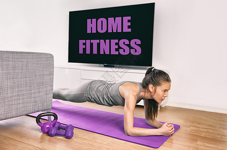 呆在家里进行健身锻炼 亚洲女孩做木板练习以锻炼核心观看健身课的电视视频 不去健身房就在电视机前训练肌肉的年轻女性图片