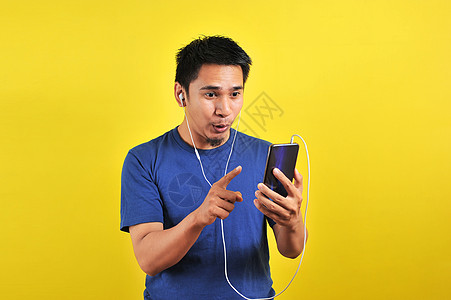 兴奋的亚洲男人的肖像 惊讶地发现一首流行歌曲互联网享受手机学习细胞体积电话微笑耳机快乐图片