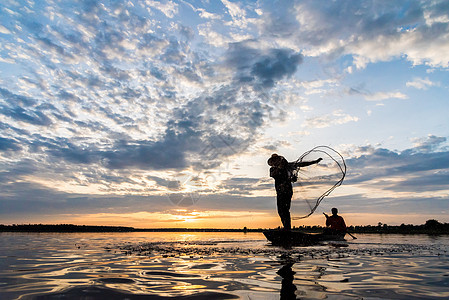 渔民在W日落时扔鱼网钓鱼的休光灯蓝色男人瓦农天空生活橙子渔夫太阳图片