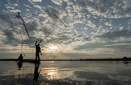 渔民在W日落时扔鱼网钓鱼的休光灯蓝色天空生活渔夫太阳男人瓦农橙子图片
