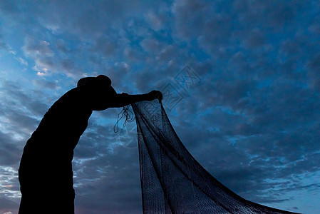 渔民在W日落时扔鱼网钓鱼的休光灯瓦农生活蓝色渔夫天空男人太阳橙子图片