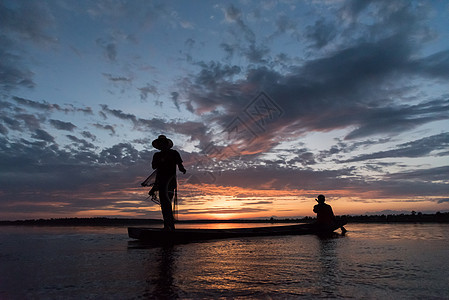 渔民在W日落时扔鱼网钓鱼的休光灯天空渔夫太阳橙子生活瓦农蓝色男人图片