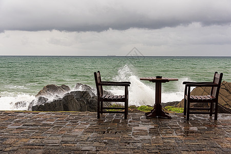 在弃置桌旁海岸岩石上坠毁的纳里海浪异国休息室支撑桌子风暴天空泡沫假期木头进口图片