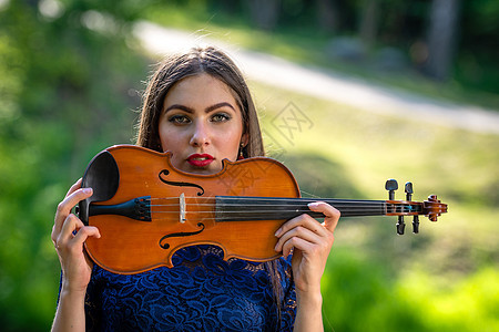 一个积极的年轻女子的画像 部分脸被小提琴的琴颈遮住了女性音乐家女士乐器黑发小提琴家眼睛头发创造力艺术图片