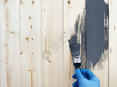 一名身戴蓝橡胶手套的工人手用灰色油漆刷漆一堵木墙地面右手工具乡村画笔维修装修条纹桌子画家图片
