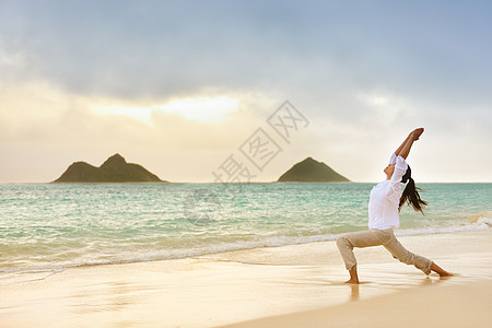 瑜伽女性在海滩摆着勇士姿势冥想图片