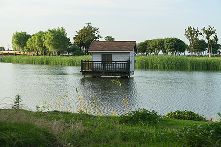 在公园的湖对面的小屋建筑草地场地花园家园闲暇船屋旅行建筑学途径图片