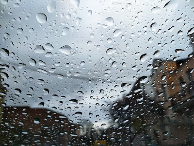 透过汽车挡风玻璃上的雨滴看到的城市街道 阴雨天的秋天天气不好 汽车挡风玻璃窗口 玻璃挡风玻璃上有雨滴图片