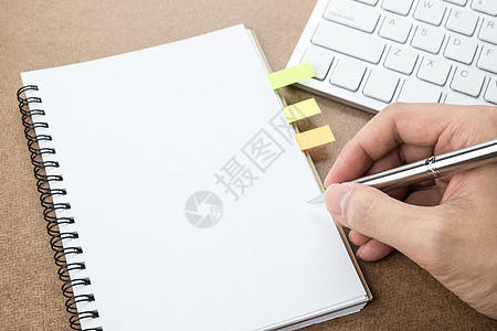 一个男人会在空白的笔记本页上写些东西螺旋学生备忘录笔记键盘计算机记事本办公室笔记本桌子图片
