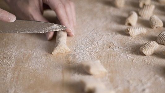 用全麦面粉制作自制素食意大利面的特写过程 家庭厨师在木砧板上切面团 传统意大利面 女人在厨房里做饭女性面粉产品木板手工土豆圆柱烹图片