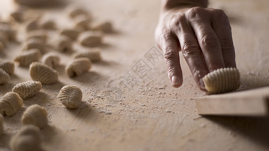 用全麦面粉制作自制素食意大利面的特写过程 家庭厨师在特殊的木制工具上爬行 gnocco 传统的意大利面食 女人在厨房里做饭午餐产图片