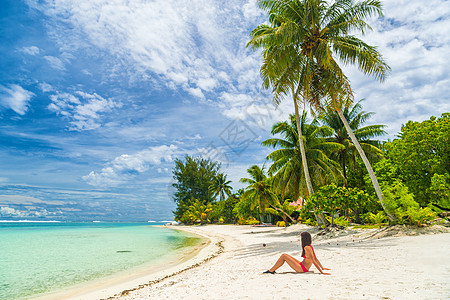 在波拉博拉塔希提比基尼海滩沙滩上躺在沙子上的 放松的女子日光浴图片