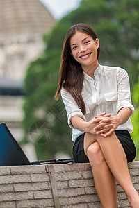快乐的多种族亚洲年轻女性在城市公园坐在户外工作休息时对着镜头微笑 20 多岁的中国白人女孩在办公室外的肖像 香港 中国 亚洲图片