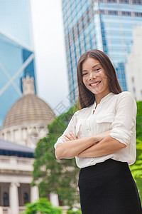 快乐自信的年轻亚洲女商务人士双臂交叉在城市背景下 香港的摩天大楼 微笑的女商务人士以职业生涯为荣 成功的领导者经理代理人职业银行图片