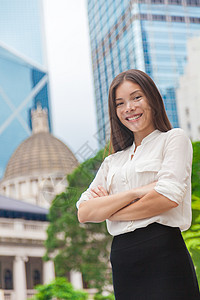 快乐自信的年轻亚洲女商务人士双臂交叉在城市背景下 香港的摩天大楼 微笑的女商务人士以职业生涯为荣 成功的领导者助手街道经理律师学图片