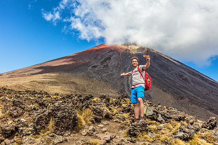 新西兰旅行社的徒步旅行者在汤加里罗高山穿越徒步小径自拍 快乐的徒步旅行者在火山山脉背景下拍摄自己的手机照片 夏日冒险图片