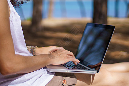 坐在海边松树林的笔记本电脑上 智能工作生活方式概念主题和生活选择等 在度假中工作的自由职业妇女近距离接近作家办公室互联网职场机动背景图片