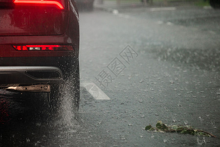 红车轮在日光城市快速行驶 有选择地集中关注 从中流出雨水车辆沥青喷涂逃避淋浴驾驶季风水坑运动飞溅图片