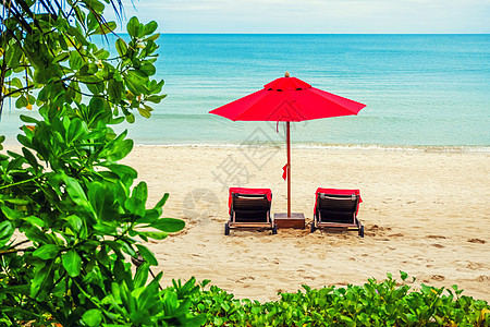 红伞在沙滩上夫妻天空躺椅地平线旅游天堂椅子海浪游客支撑图片