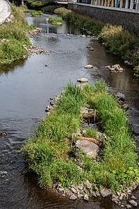 狭小的河流穿过草原植物绿色石工支撑灰色结垢河岸植被石头栏杆图片