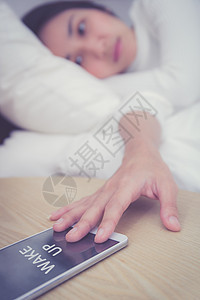 熟睡妇女的手在手机上用闹钟唤醒电话卧室睡眠技术细胞时间警报桌子女性苏醒图片