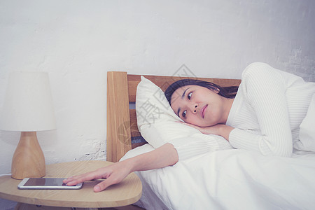 熟睡妇女的手在手机上用闹钟唤醒假期电话时间细胞桌子女性苏醒警报卧室睡眠图片