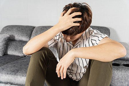 青年男子坐在沙发上时头部疼痛 保健医疗或日常生活概念 在家庭里 男方需要照顾孩子药品身体伤害悲伤头痛成人情感男性痛苦疾病图片