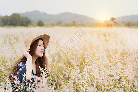 日落时坐在草地上的年轻时装女士的夏季肖像图片